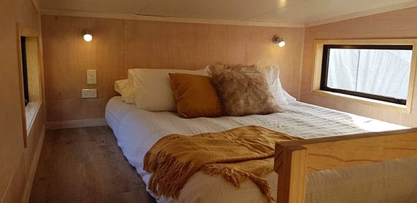 King sized bed in upstairs bedroom of a Tiny Home