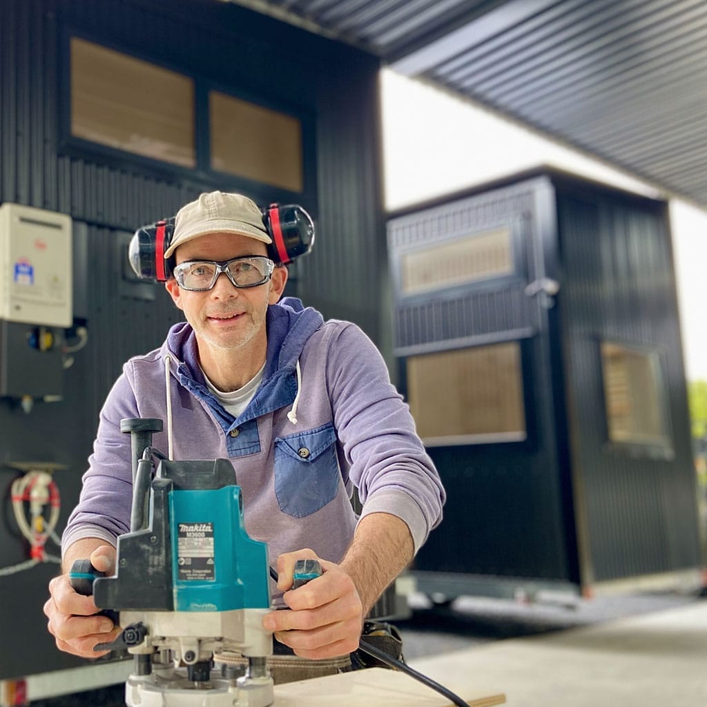 Glen working at the Fox Cabins workshops in Raglan with two Tiny Homes ready to head out the door.